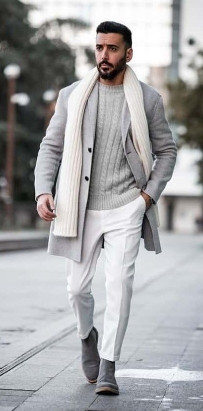 A grey outfit that has grey colored long overcoat and cream scarf. Also wearing a grey sweater inside and grey boots A grey outfit that has grey colored long overcoat and cream scarf. Also wearing a grey sweater inside and grey boots