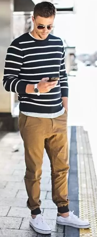beige chino joggers with blue and white stripped full-sleeved tshirt and white sneakers accessorized with shades adn a watch beige chino joggers with blue and white stripped full-sleeved tshirt and white sneakers accessorized with shades adn a watch