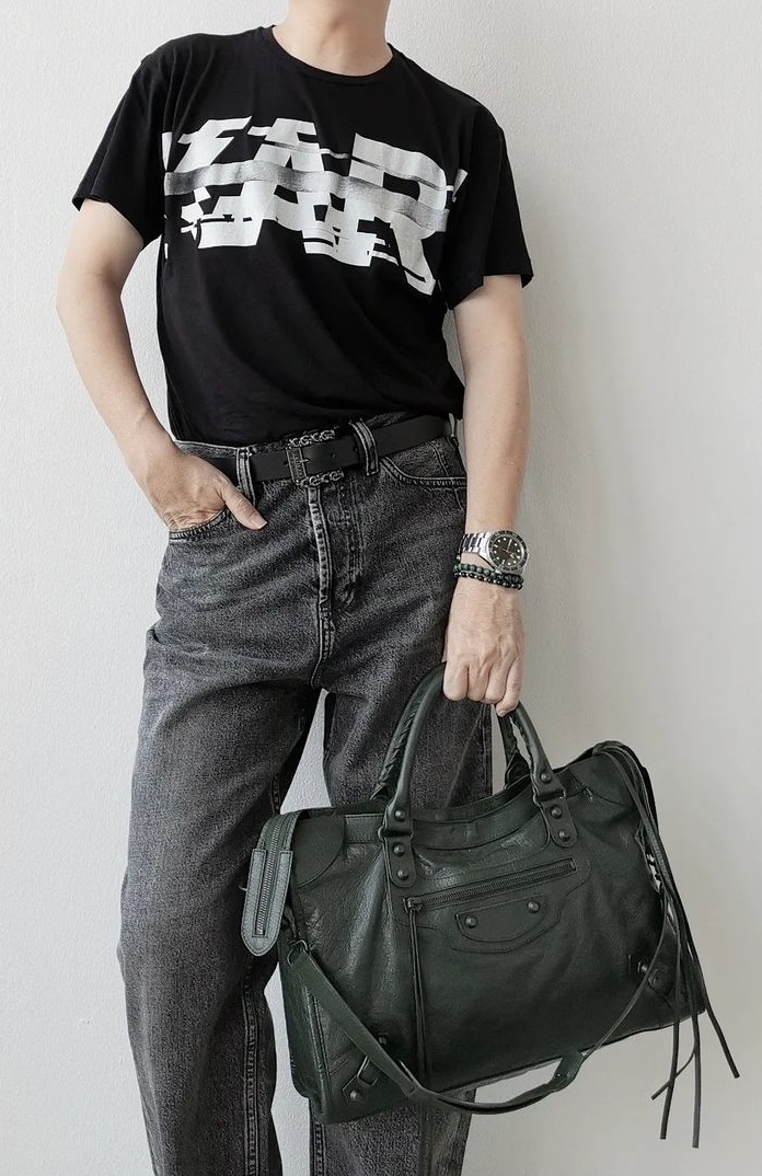 a black tshirt with a grey denims, accessorized with Balenciaga City Bag, a watch and a bracelet being must-have products to own a black tshirt with a grey denims, accessorized with Balenciaga City Bag, a watch and a bracelet being must-have products to own