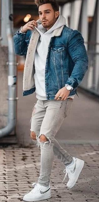 a denim jacket with grey hoodie and ripped denims, accessorized with the sneaker brand Nike and a watch a denim jacket with grey hoodie and ripped denims, accessorized with the sneaker brand Nike and a watch