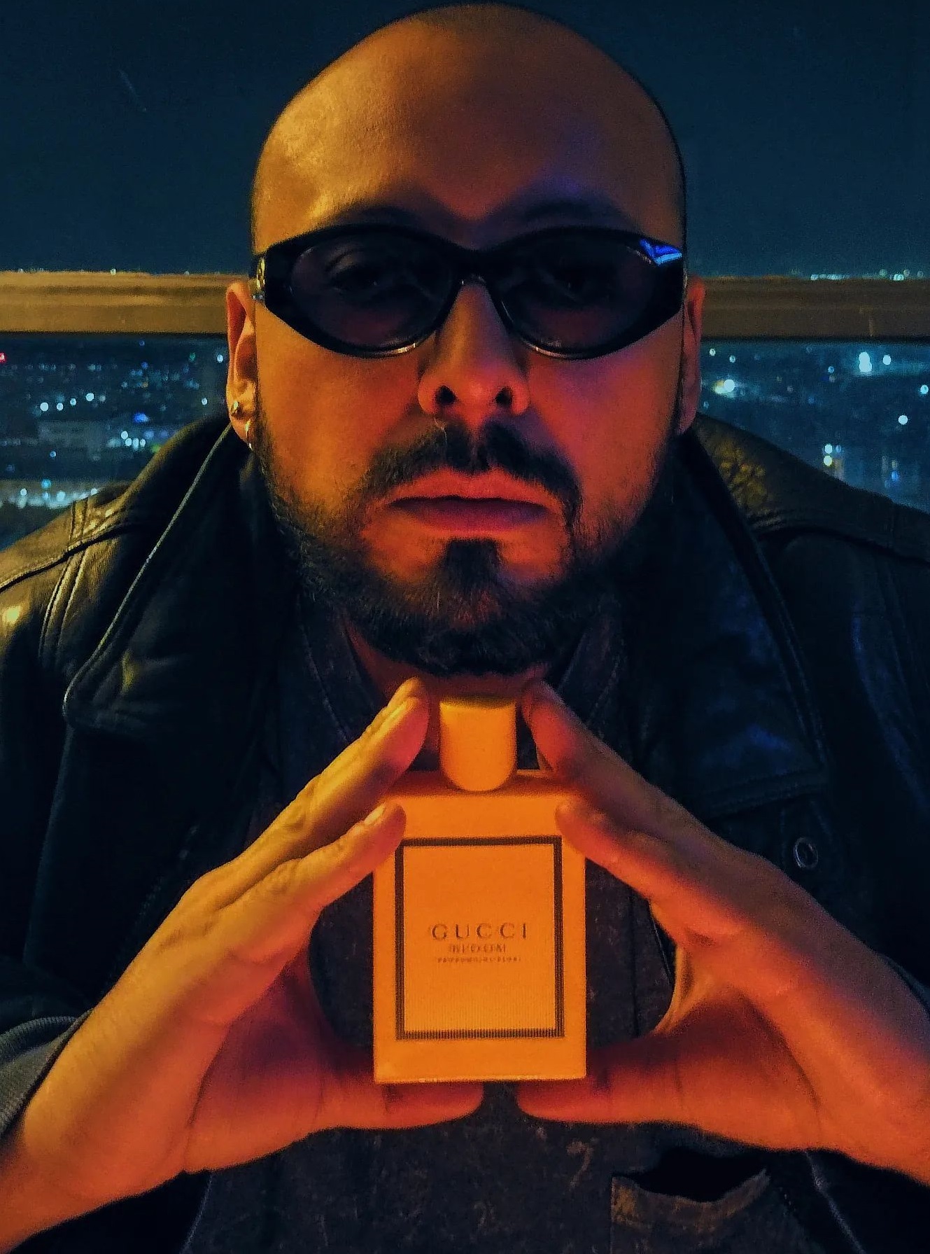 Gucci perfume being a must-have product to own, a man holding it, who is wearing shades Gucci perfume being a must-have product to own, a man holding it, who is wearing shades