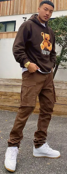street style cargo pant in brown color with brown hooddie, accessorized with a watch and wearing a white sneaker street style cargo pant in brown color with brown hooddie, accessorized with a watch and wearing a white sneaker